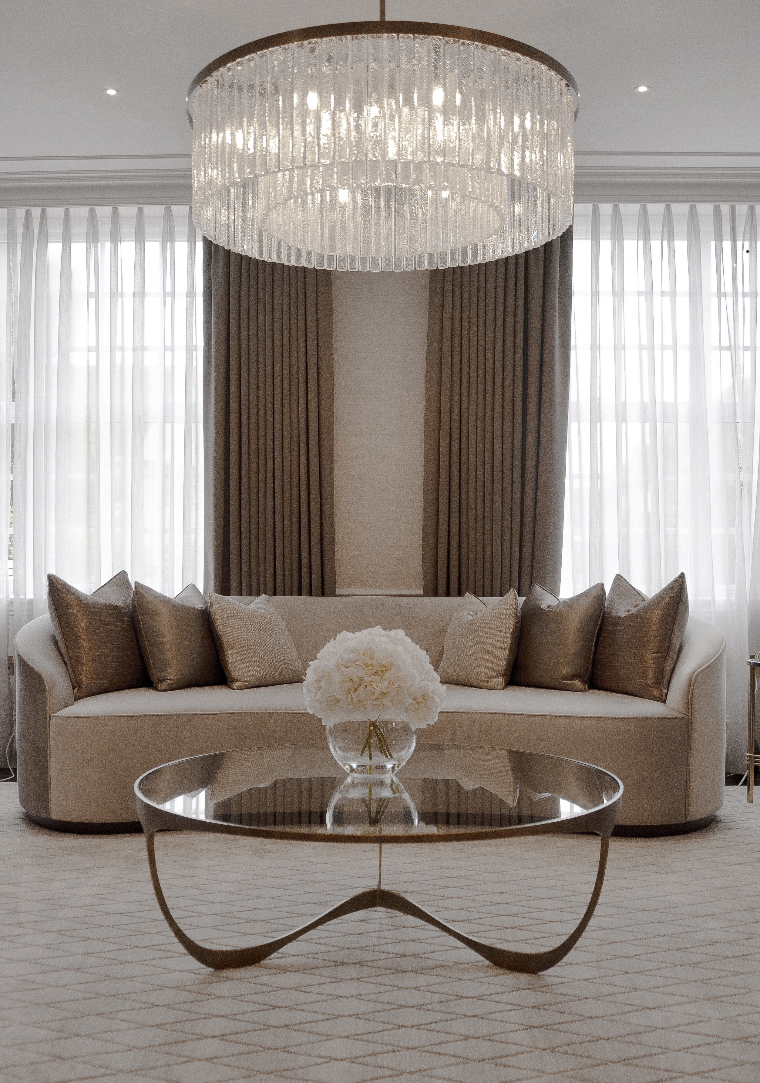 Living room with a curved sofa and crystal chandelier by Aleph Studio